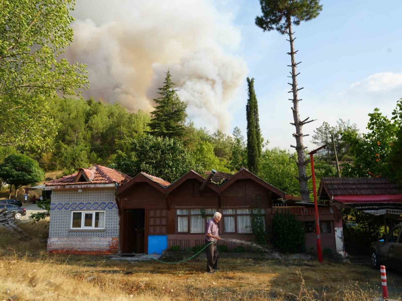 Elinde hortumla otları ıslatarak evini yangından korumaya çalıştı